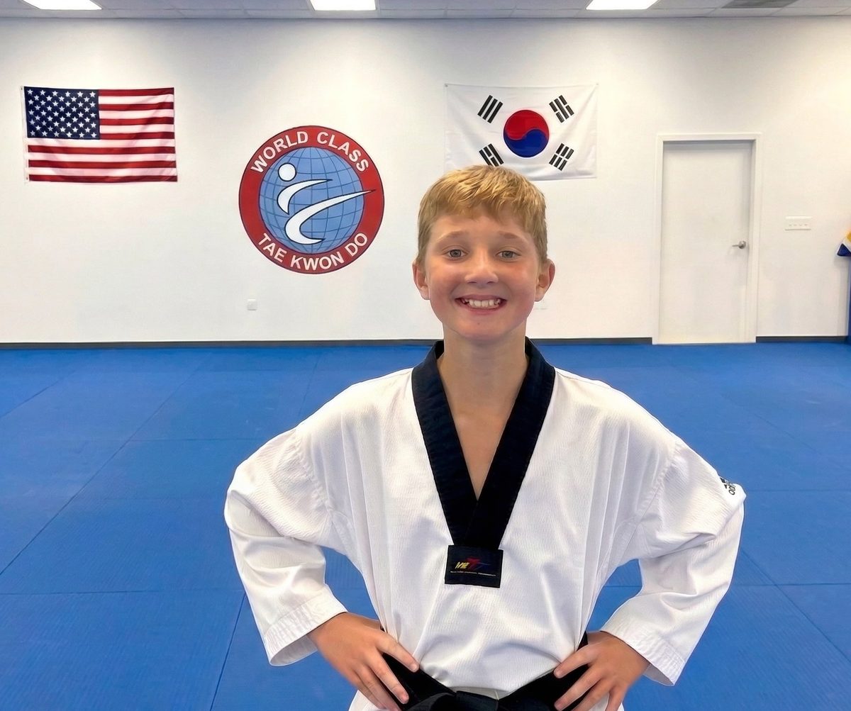 A young student in uniform smiling at World Class Tae Kwon Do